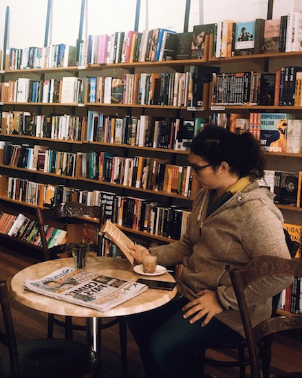 Person drinking coffee at the Hares & Hyenas book shop