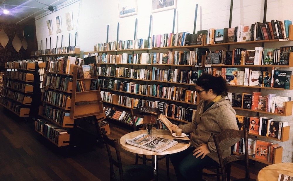 Person drinking coffee at the Hares & Hyenas book shop